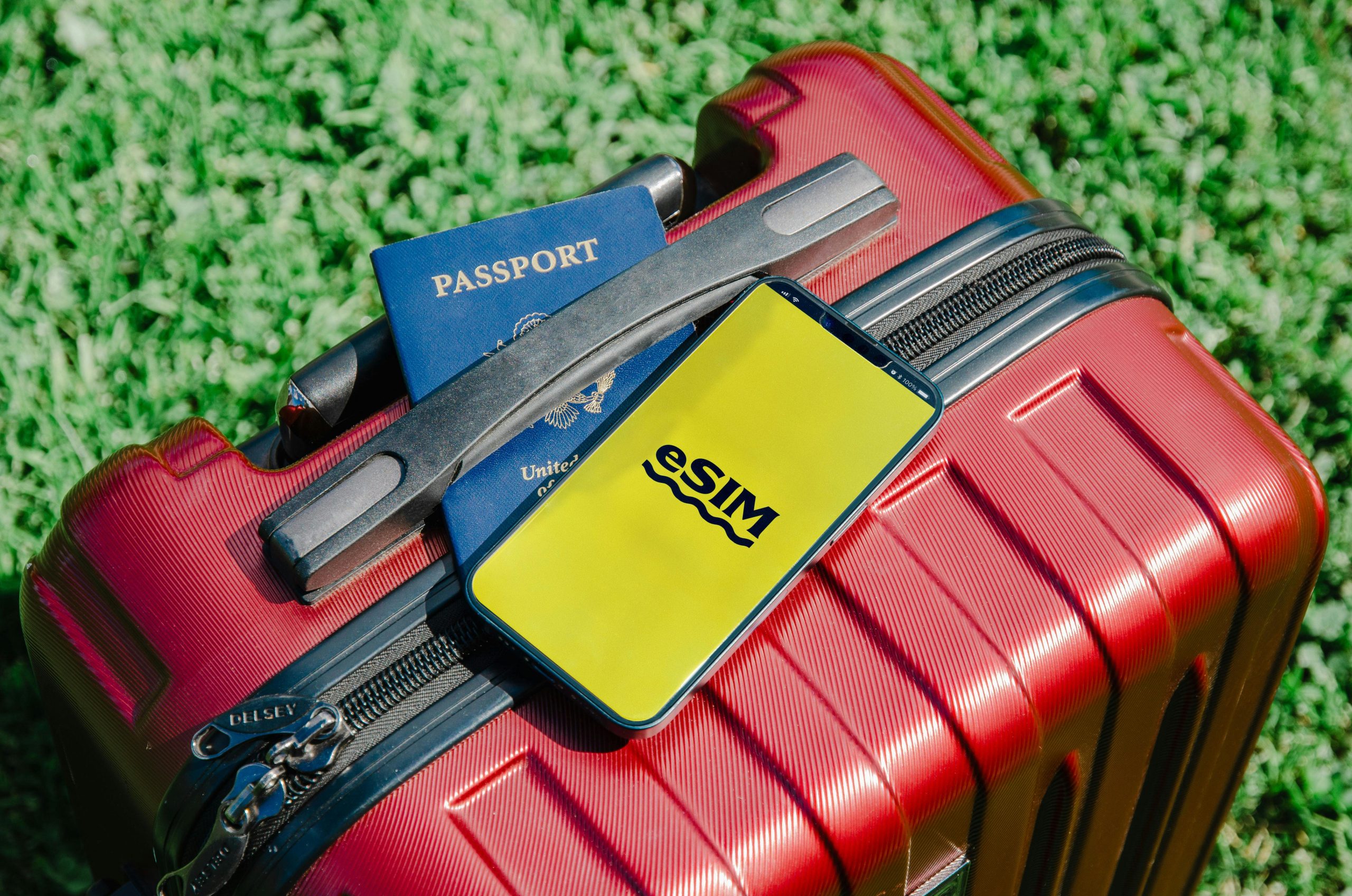The image shows a close-up of a red suitcase with a smartphone displaying the best eSIM for travel.